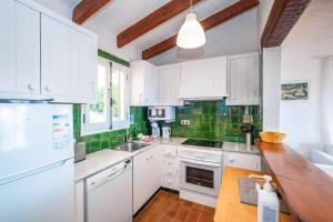 a kitchen with white cabinets and green tiles at Villa Binisol in Binibeca
