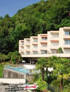 a large white building with a swimming pool and a mountain at Bella-Lugano in Aldesago
