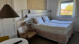 a bedroom with a bed and a chair and a window at Hine Bakke Bed And Breakfast in Rudkøbing