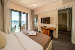 a hotel room with a bed and a desk and a window at Hotel Aleksandar Rafailovići in Budva