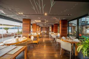 a restaurant with wooden tables and chairs and windows at Hotel Aleksandar Rafailovići in Budva