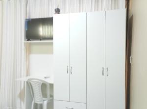 a pair of white cabinets in a room with a chair at Ada H5 in Ciudad del Este