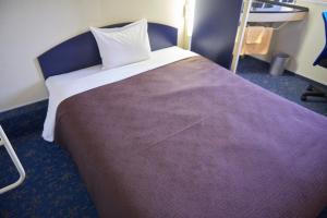 a bedroom with a large bed with a purple blanket at Hotel Select Inn Isesaki in Isesaki