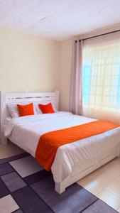 a bedroom with a bed with orange pillows and a window at Luxe homes 1b in Kabuku