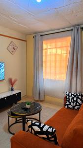 a living room with a couch and a table and a window at Luxe homes 1b in Kabuku
