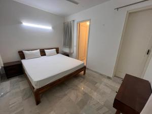 a bedroom with a bed with white sheets and a table at Giostay Residency in New Delhi