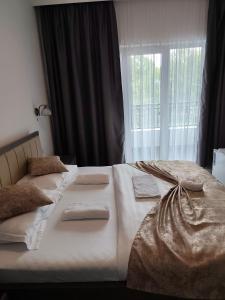two beds in a bedroom with a window at Pensiune Restaurant Perla in Sângeorz-Băi