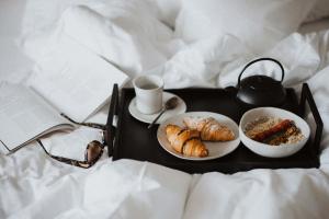 a breakfast tray with croissants and coffee on a bed at SIEGI apartments & retreat - Merano Südtirol in Parcines
