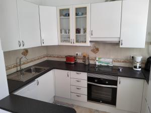 a white kitchen with white cabinets and a sink at Lorarno in Praia do Carvoeiro