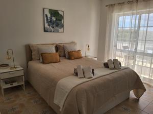 a large bed in a bedroom with a large window at Lorarno in Praia do Carvoeiro