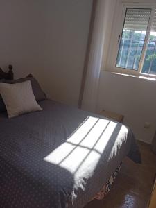 a bedroom with a bed with the sun shining through a window at Casa del Abuelo in Setenil
