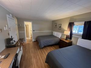 a hotel room with two beds and a desk at Martin's Motel USA in Madawaska