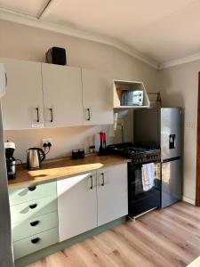 a kitchen with white cabinets and a black refrigerator at Spacious cottage with a private garden in Somerset West