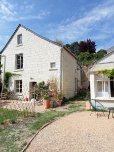 a white brick house with a bench in front of it at Gite du Vidame in Montsoreau