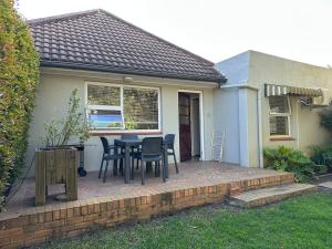 a patio with chairs and a table in front of a house at Spacious cottage with a private garden in Somerset West