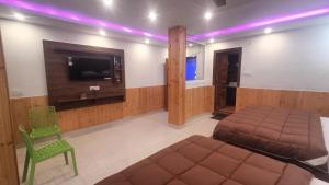 a bedroom with a bed and a tv and a chair at RK Residency Hotel & Resturant in Ukhimath