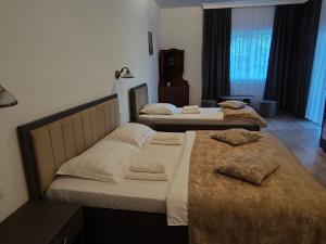 two beds in a hotel room with two beds at Pensiune Restaurant Perla in Sângeorz-Băi +14 photos