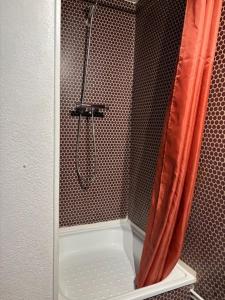 a shower with an orange shower curtain in a bathroom at Maisonnette cosy à 400 m de la plage - Saint Cyprien in Saint-Cyprien-Plage