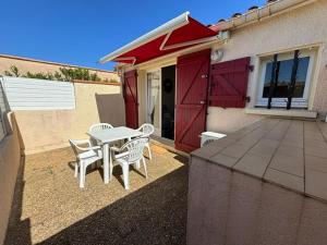 a patio with a table and chairs in front of a house at Maisonnette cosy à 400 m de la plage - Saint Cyprien in Saint-Cyprien-Plage +8 photos
