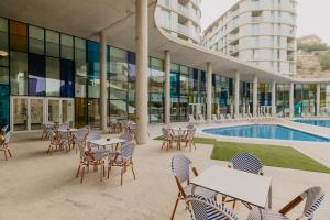 a building with tables and chairs and a pool at Palladium Hotel Peñiscola in Peniscola