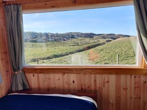 a window in a bedroom with a view of a hill at Bothan na Mara in Valtos