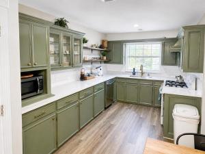 a kitchen with green cabinets and white counter tops at Peach Door Cottage in Lufkin