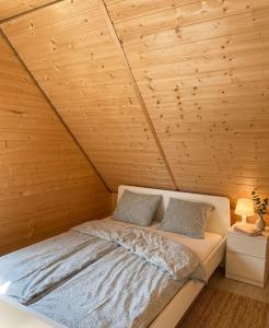 a bed in a room with a wooden ceiling at Domki Hippalos Jarosławiec in Jarosławiec