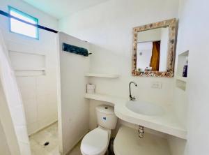 a white bathroom with a toilet and a sink at Casa Violeta Beach House in Rincón