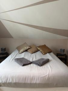 a white bed with three pillows on top of it at Villa avec piscine intérieure, proche Strasbourg in Holtzheim