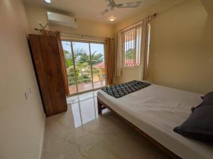a bedroom with a bed and a large window at Shree's Seaside Homestay - Sea Pearl in Magdāl
