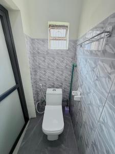 a small bathroom with a toilet and a window at Biez Homestay in Karatu