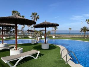 a swimming pool with chairs and umbrellas and the ocean at Espacio I in Cullera