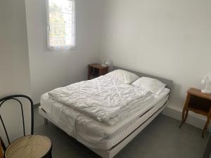 an unmade bed in a white room with a window at hirondelle 1 in Noirmoutier-en-l'lle