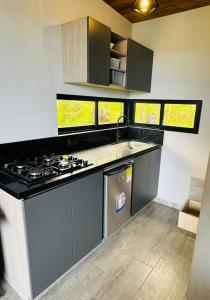 a kitchen with a stove and a sink and some windows at Cabaña MonteCristo in El Peñol