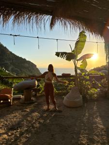 a woman standing on the beach with the sunset in the background at Kidrak Camping NAMASTE in Faralya