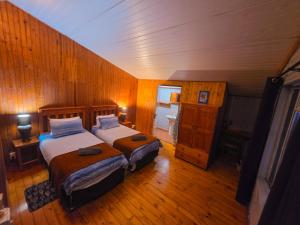two beds in a room with wooden walls and wood floors at Reefteach Lodge in Sodwana Bay +136 photos