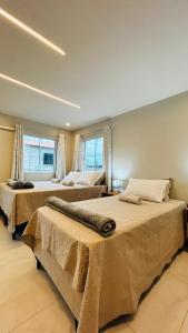 two beds in a room with two windows at Blessed House Atins in Atins