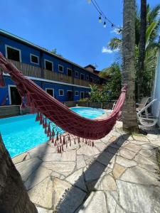 a hammock in front of a hotel with a pool at Maré Alta 400 mt da praia de Maresias in Maresias
