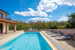 a swimming pool with lounge chairs next to a house at Lux pool Villa Zen - located in peaceful village near Rijeka and Opatija in Klana