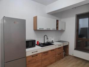 a kitchen with a stainless steel refrigerator and wooden cabinets at Voievozilor Residence in Constanţa