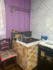 a kitchen with a stove and a counter with a chair at Sítio Meu Cantinho in Benedito Novo