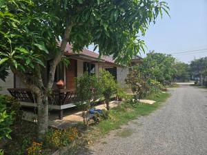 a house with a table and trees next to a road at Cocoa Hut in Mae Chan