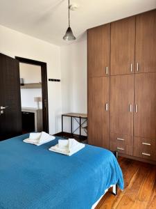 a bedroom with a blue bed and wooden cabinets at HillSide Apartments - 02 in Agia Galini