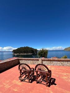 two benches sitting on top of a red floor with the water at Puma Punku Lodge in Isla Chillica