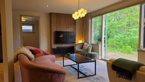 a living room with a couch and two chairs and a tv at Huisje Jan in Hoenderloo