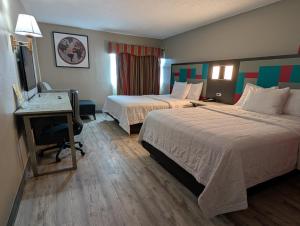 a hotel room with two beds and a desk at Ramada by Wyndham East Orange in East Orange +22 photos