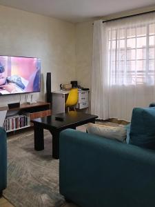 a living room with a couch and a tv at Classy bedroom Ngong in Ngong