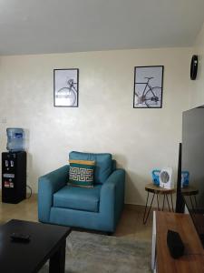 a blue couch in a living room with three pictures on the wall at Classy bedroom Ngong in Ngong +2 photos