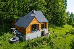 a small house with a black roof in a field at Chata Malenovice in Malenovice +27 photos