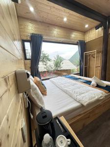 a large bed in a wooden room with a window at Mây Đá Homestay in Loung Co